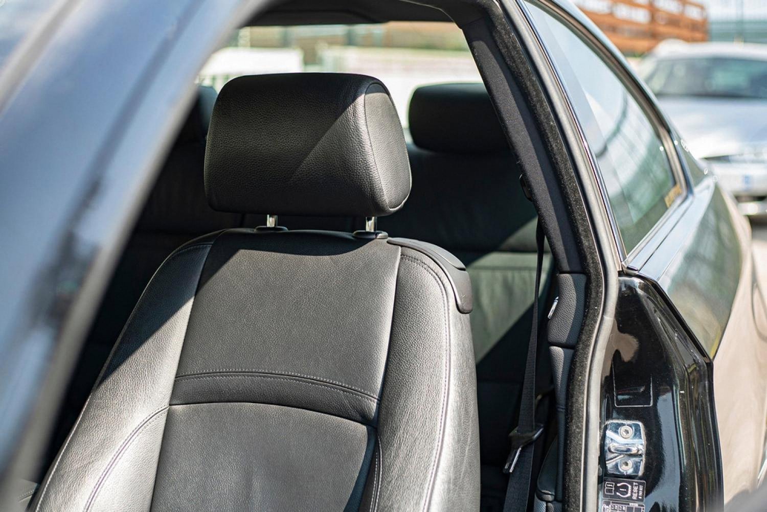 Freshly cleaned black leather driver seat and door pillar of a used sedan